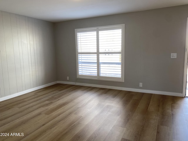 empty room featuring hardwood / wood-style flooring and wooden walls