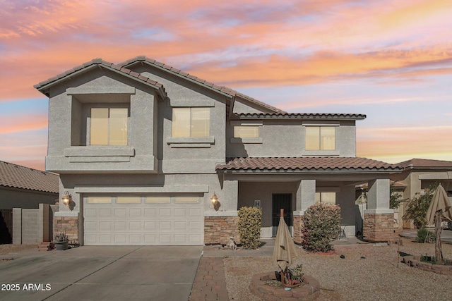 view of front of house featuring a garage, concrete driveway, stone siding, and stucco siding