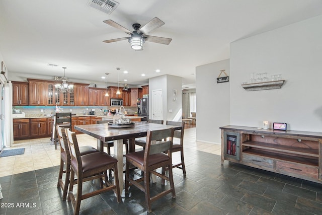 dining area with recessed lighting, visible vents, stone tile flooring, and ceiling fan with notable chandelier