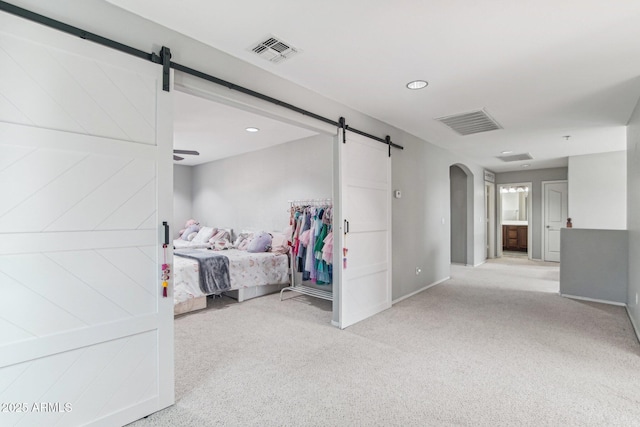 bedroom featuring carpet floors, visible vents, and a barn door