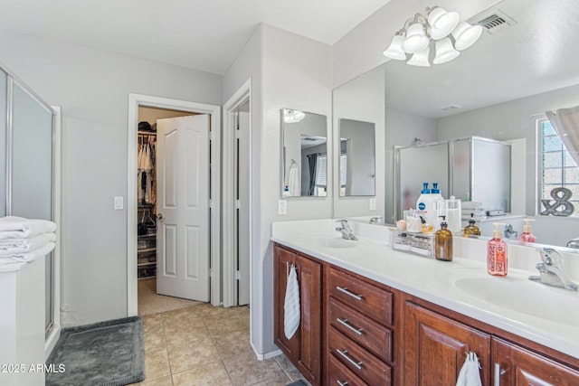 bathroom featuring double vanity, a stall shower, visible vents, a spacious closet, and a sink