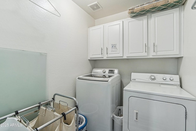 laundry room featuring cabinet space, visible vents, and washing machine and clothes dryer