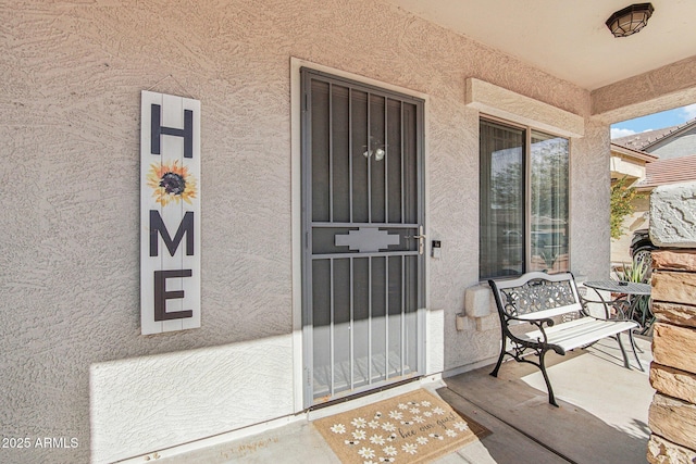 entrance to property featuring covered porch and stucco siding