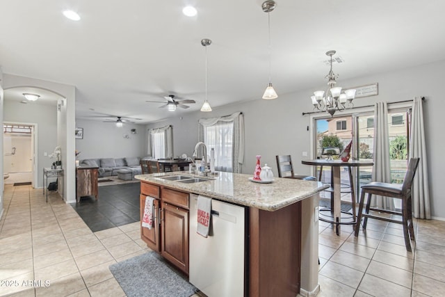 kitchen featuring arched walkways, light tile patterned floors, open floor plan, a sink, and dishwasher