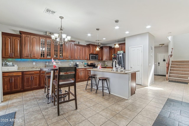 kitchen with light stone countertops, visible vents, appliances with stainless steel finishes, and decorative backsplash