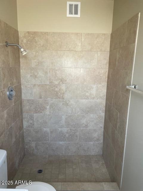 bathroom featuring tiled shower and toilet