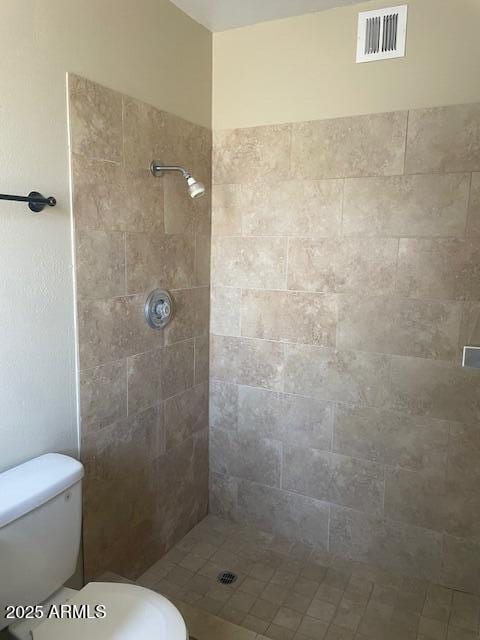 bathroom featuring a tile shower and toilet