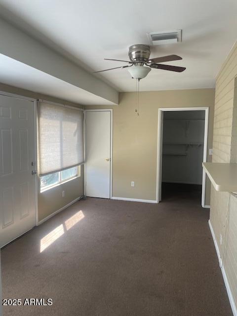 empty room featuring dark carpet and ceiling fan