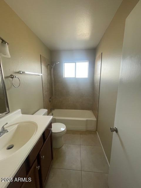 full bathroom featuring tile patterned flooring, vanity, tiled shower / bath combo, and toilet