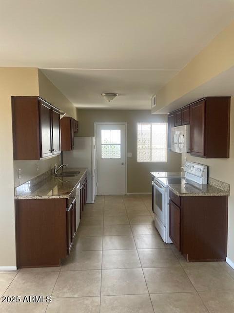 kitchen featuring sink, light stone counters, white appliances, and light tile patterned floors