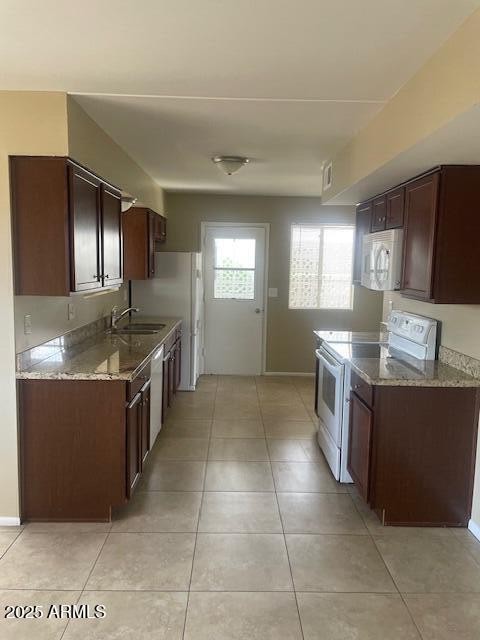 kitchen featuring light tile patterned flooring, light stone countertops, sink, and white appliances