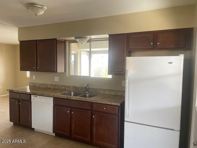 kitchen featuring white appliances, dark stone counters, sink, and light tile patterned floors