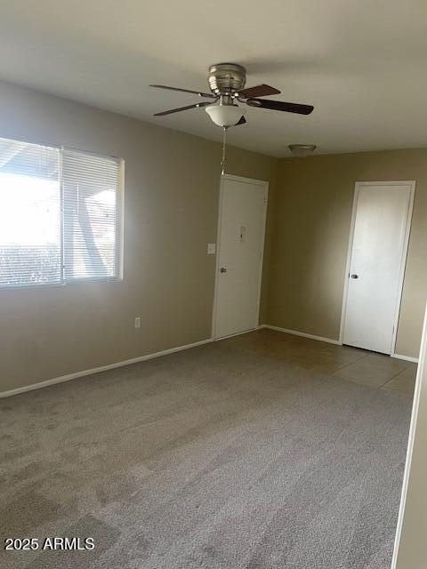 carpeted spare room featuring ceiling fan