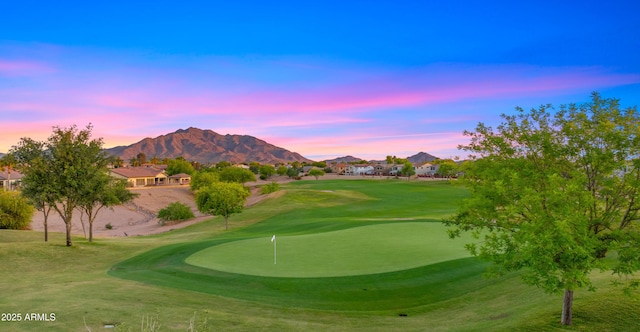 view of property's community featuring a putting area, golf course view, a mountain view, and a yard
