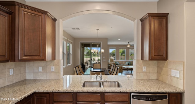 kitchen with dishwasher, a sink, light stone counters, and arched walkways