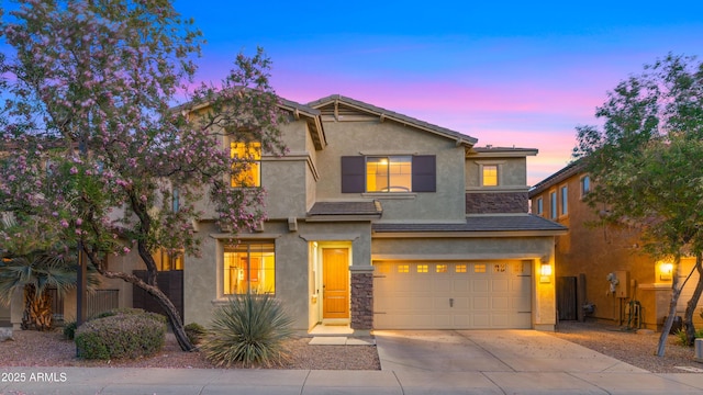 traditional home featuring an attached garage, concrete driveway, stucco siding, and stone siding