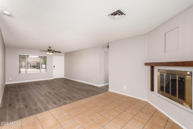 unfurnished living room featuring ceiling fan, a textured ceiling, and light hardwood / wood-style floors