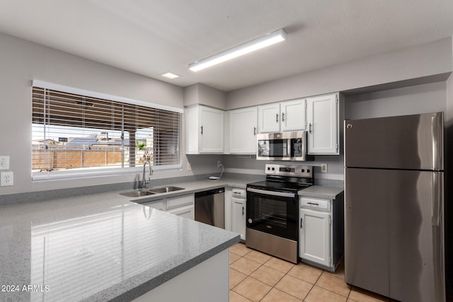 kitchen with stainless steel appliances, white cabinets, light tile patterned floors, and sink