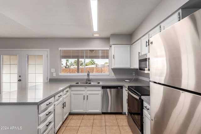 kitchen featuring white cabinets, kitchen peninsula, light tile patterned floors, stainless steel appliances, and sink