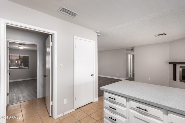 kitchen featuring white cabinets, light tile patterned flooring, and a textured ceiling