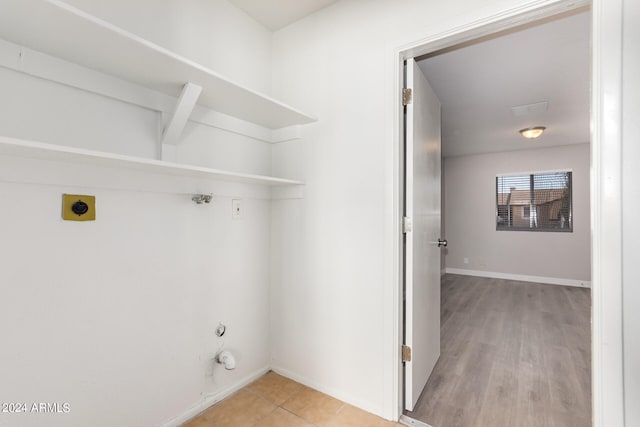 clothes washing area with light hardwood / wood-style flooring, hookup for an electric dryer, and hookup for a gas dryer