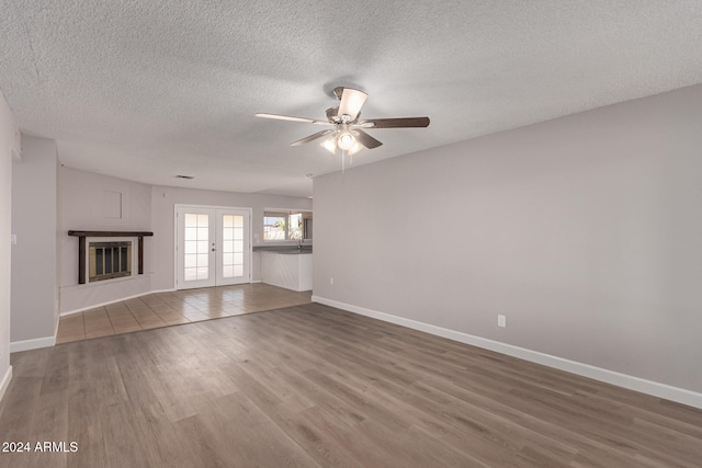 unfurnished living room with wood-type flooring, a textured ceiling, french doors, and ceiling fan