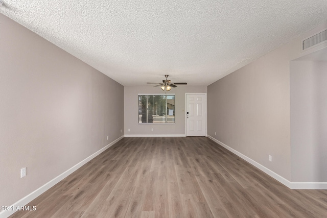 empty room with ceiling fan, a textured ceiling, and light hardwood / wood-style floors