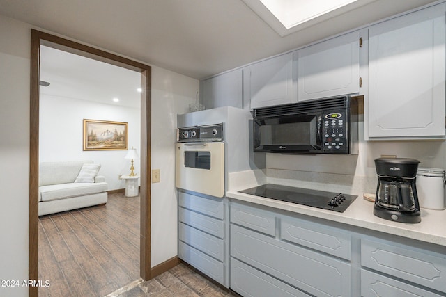 kitchen with white cabinets, dark hardwood / wood-style floors, and black appliances