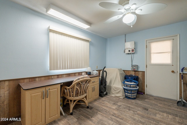 office with ceiling fan, wooden walls, built in desk, and dark hardwood / wood-style flooring