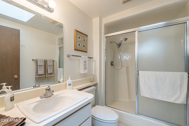 bathroom with a skylight, vanity, toilet, and an enclosed shower