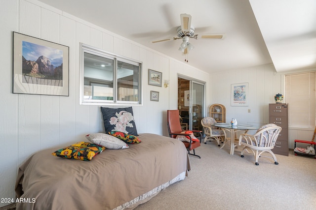 bedroom featuring ceiling fan, a closet, wood walls, and carpet flooring