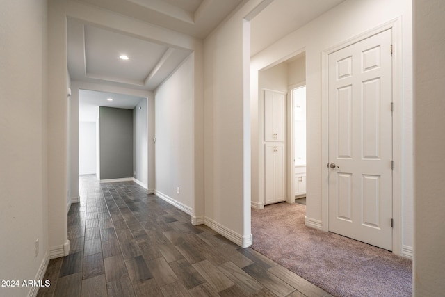 hallway with a raised ceiling and dark hardwood / wood-style flooring