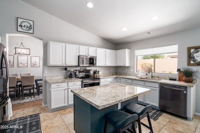 kitchen with appliances with stainless steel finishes, an inviting chandelier, a sink, a kitchen breakfast bar, and lofted ceiling