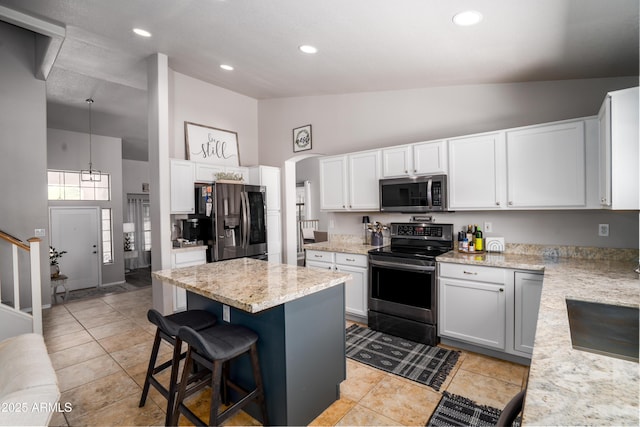 kitchen with appliances with stainless steel finishes, a breakfast bar area, high vaulted ceiling, a center island, and white cabinetry