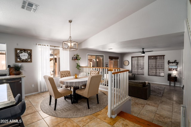 dining space featuring light tile patterned flooring, ceiling fan with notable chandelier, baseboards, lofted ceiling, and visible vents