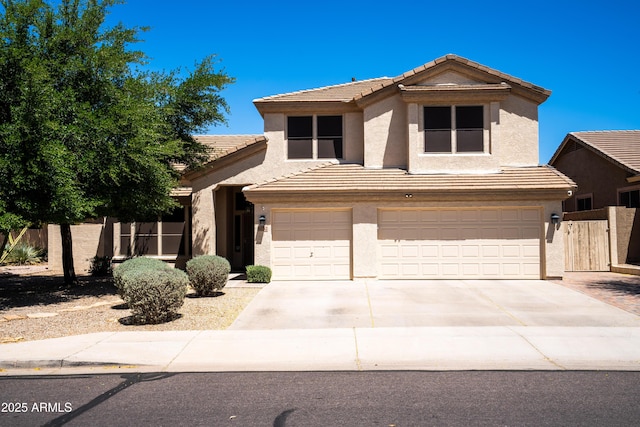 traditional-style home featuring a tiled roof, driveway, a garage, fence, and stucco siding