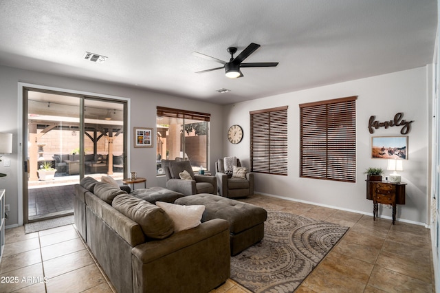 living room with visible vents, light tile patterned flooring, baseboards, a textured ceiling, and a ceiling fan