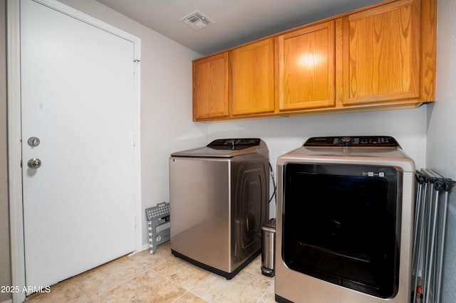 laundry room with light tile patterned floors, washer and dryer, cabinet space, and visible vents