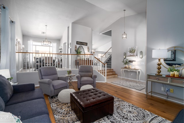 living room with a notable chandelier, stairs, baseboards, wood finished floors, and vaulted ceiling