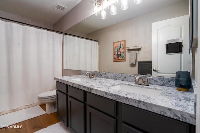 bathroom with toilet, visible vents, a sink, and wood finished floors