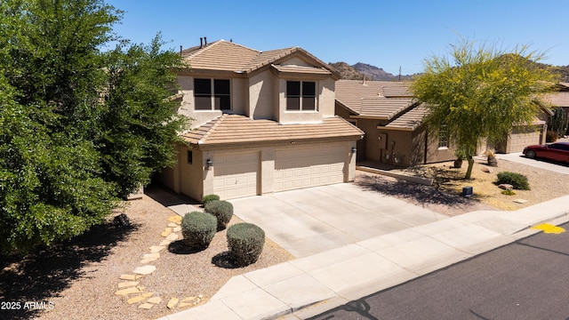 traditional-style home featuring stucco siding, a tiled roof, an attached garage, a mountain view, and driveway