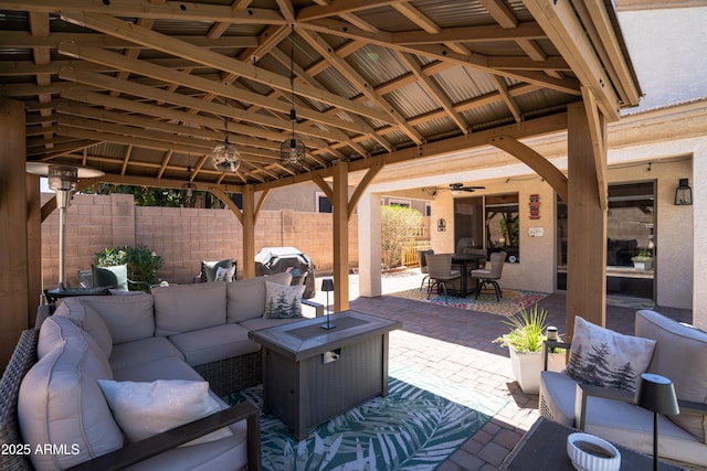 view of patio featuring fence, a gazebo, an outdoor hangout area, outdoor dining area, and a ceiling fan