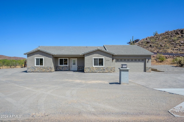 ranch-style house with stucco siding, an attached garage, stone siding, driveway, and a tiled roof