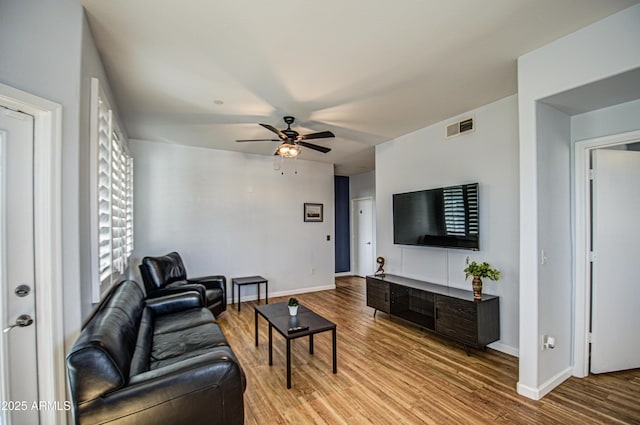 living area featuring a ceiling fan, baseboards, visible vents, and wood finished floors