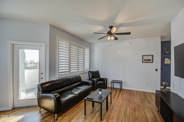 living room with ceiling fan, baseboards, and wood finished floors