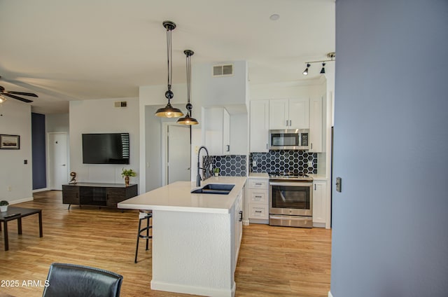 kitchen featuring a sink, appliances with stainless steel finishes, white cabinets, and backsplash