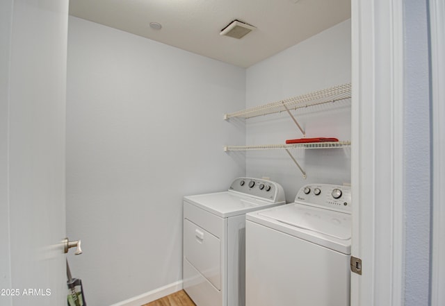 washroom featuring laundry area, visible vents, light wood-style floors, baseboards, and washing machine and clothes dryer