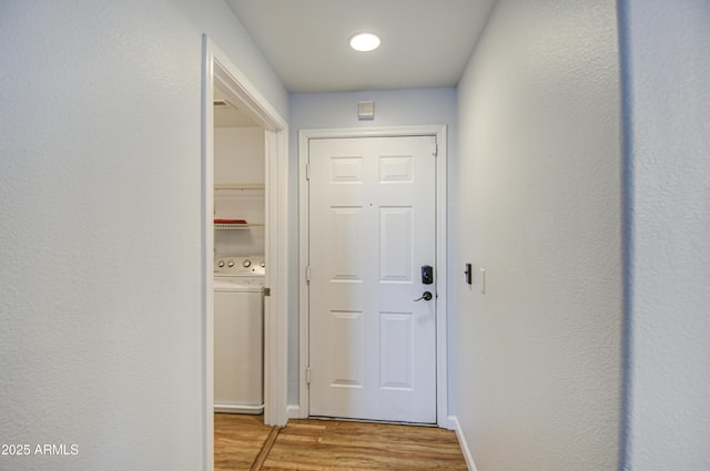 entryway with washer / dryer, light wood-style floors, and baseboards