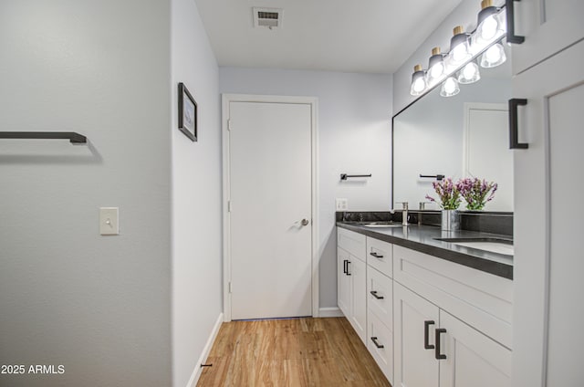 bathroom with double vanity, visible vents, a sink, and wood finished floors