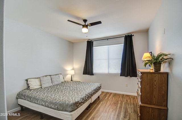 bedroom featuring ceiling fan, baseboards, and wood finished floors